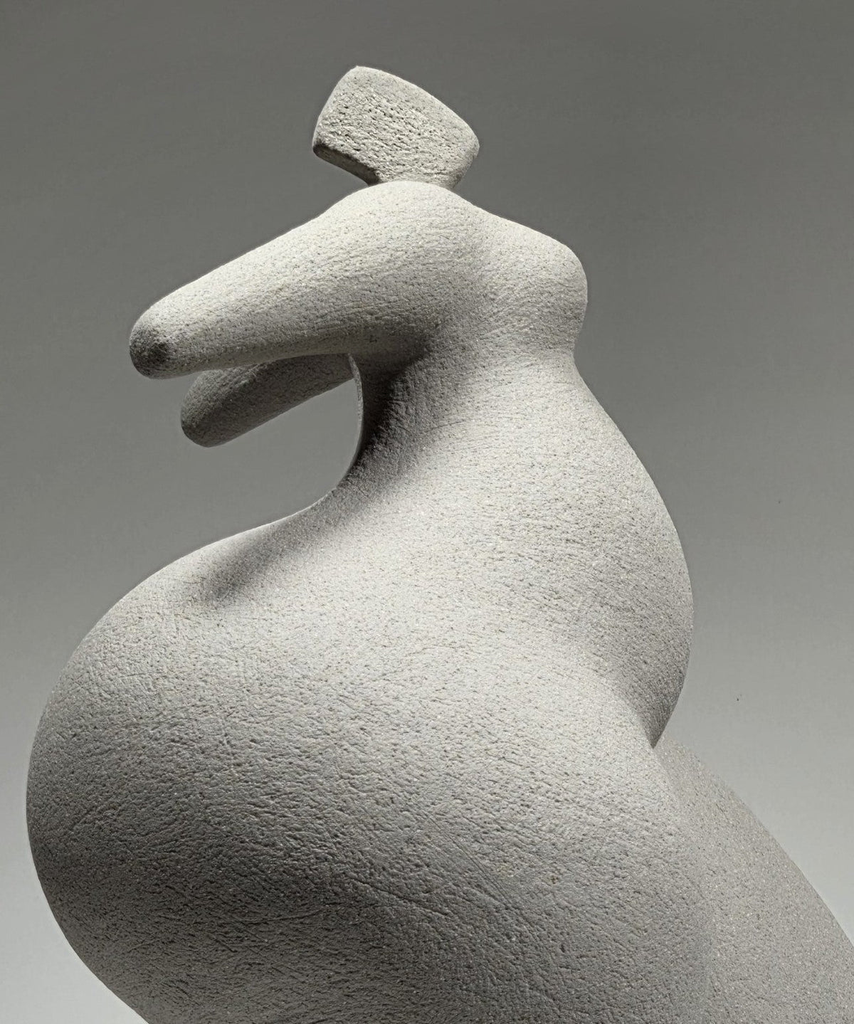 Close-up detail of Abandon, hand-built ceramic sculpture by Rachel Peters, coiled in grey grogged stoneware, left unglazed, showing the textured surface and dynamic form of the upper body