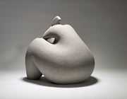 Abstract grey ceramic sculpture of a figure on a grey background