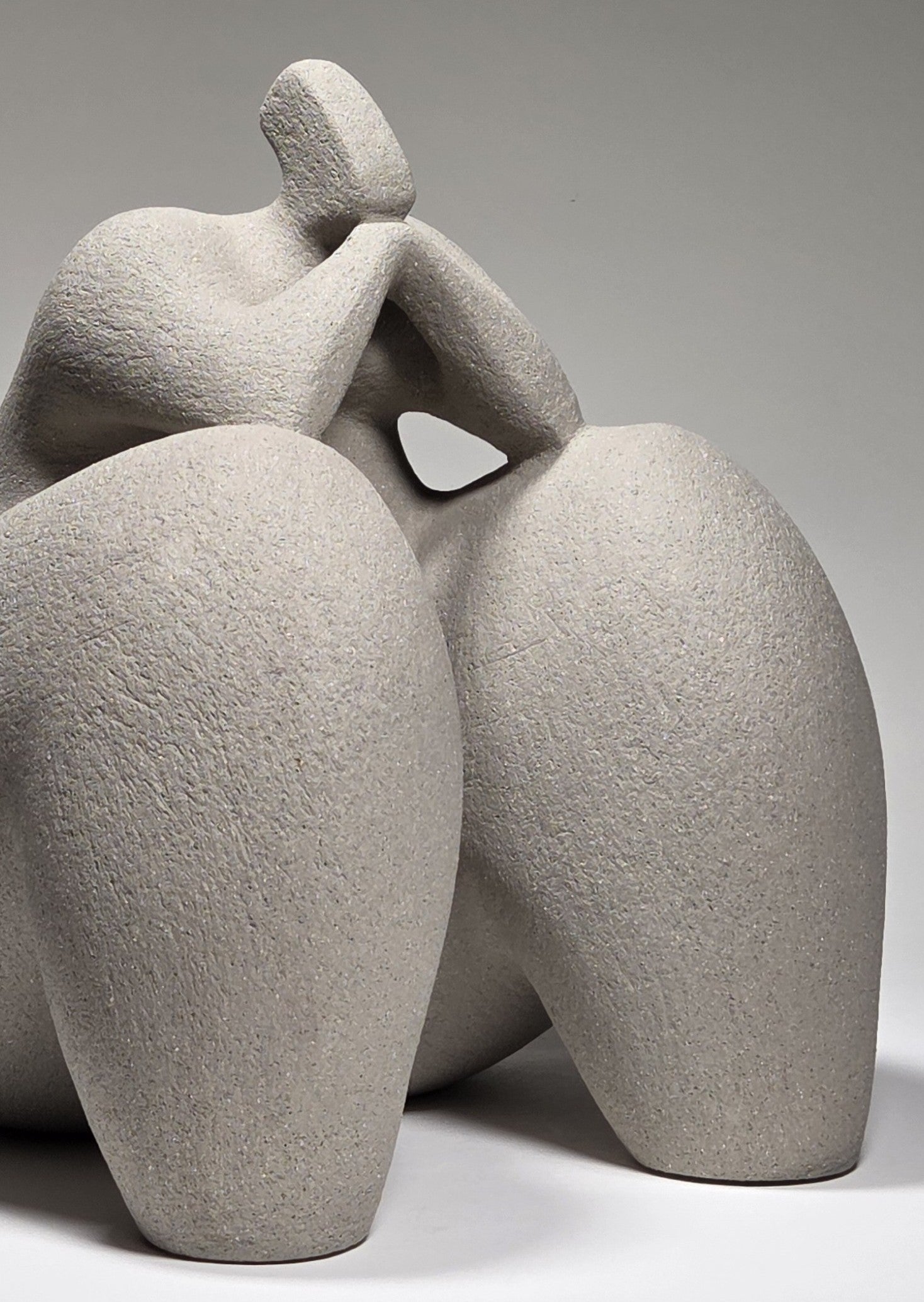 Abstract grey ceramic sculpture of a figure on a grey background