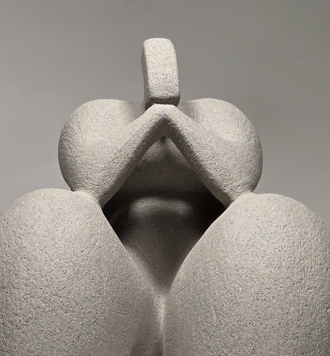 Close up of Abstract grey ceramic sculpture of a figure on a grey background