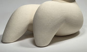 Close up of White ceramic sculpture of a reclining figure on a grey background