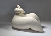White ceramic sculpture of a reclining figure on a grey background