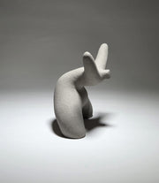 Grey abstract ceramic sculpture of a figure bent backwards with arms thrown outwards titled rock star on a light grey background