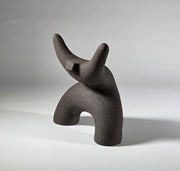 Black abstract ceramic sculpture of a figure bent backwards with arms thrown outwards titled rock star on a light grey background