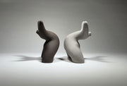 Black and grey abstract ceramic sculptures of two figures bent backwards with arms thrown outwards titled rock star on a light grey background