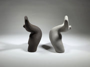 Black and grey abstract ceramic sculptures of two figures bent backwards with arms thrown outwards titled rock star on a light grey background