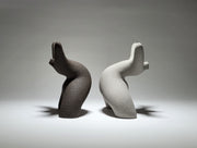 Black and grey abstract ceramic sculptures of two figures bent backwards with arms thrown outwards titled rock star on a light grey background