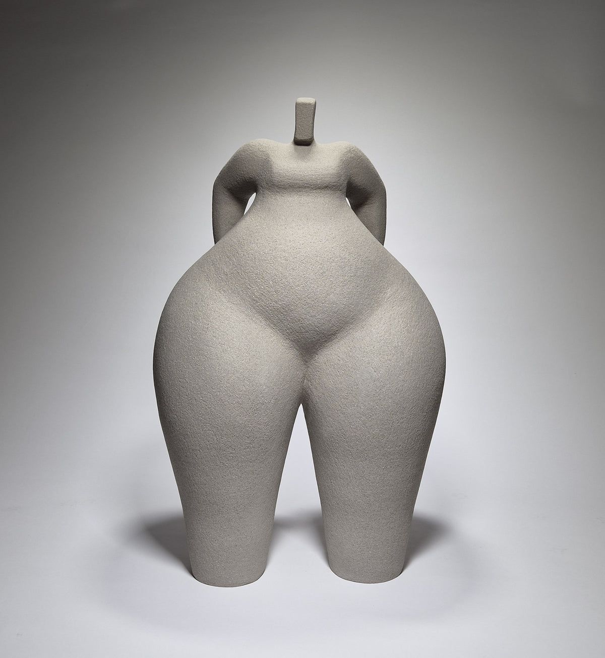 Still Standing, a hand-built ceramic sculpture of an abstracted female form in grey stoneware clay, grogged texture against a light grey background.