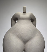 Close up shot of Still Standing, a hand-built ceramic sculpture of an abstracted female form in grey stoneware clay, grogged texture against a light grey background.
