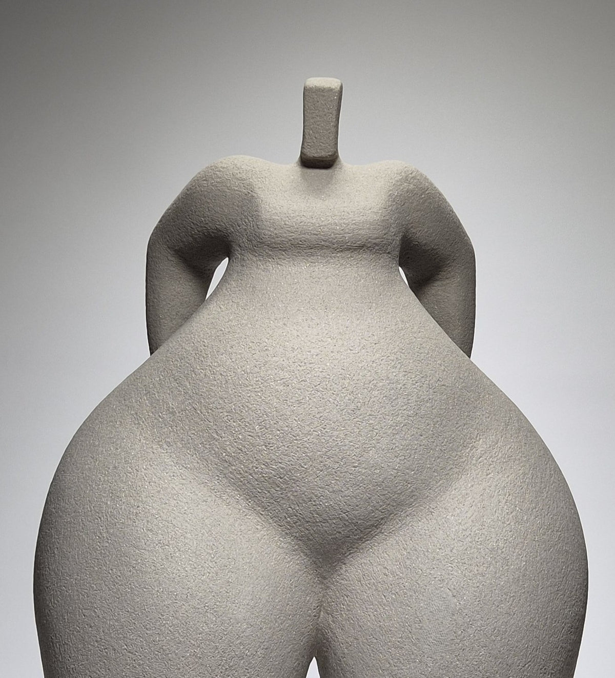 Close up shot of Still Standing, a hand-built ceramic sculpture of an abstracted female form in grey stoneware clay, grogged texture against a light grey background.