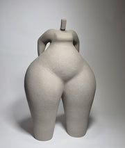 Still Standing, a hand-built ceramic sculpture of an abstracted female form in grey stoneware clay, grogged texture against a light grey background.