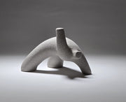 Abstract grey ceramic figure arching backwards with one arm on the floor and one stretched upwards pictures on a light grey background