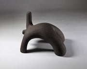Abstract black ceramic figure arching backwards with one arm on the floor and one stretched upwards pictures on a light grey background