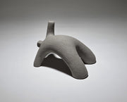 Abstract grey ceramic figure arching backwards with one arm on the floor and one stretched upwards pictures on a light grey background